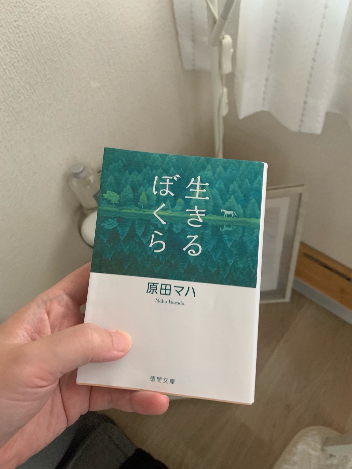 手に持った文庫本『生きるぼくら』。自然を背景にしたカバーが印象的
