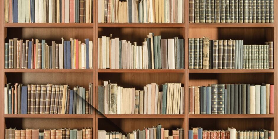 本がぎっしりと並んだ木製の書棚。物語が静かに息づく図書館の一角のような風景で、本の重みと温かみを感じさせる。