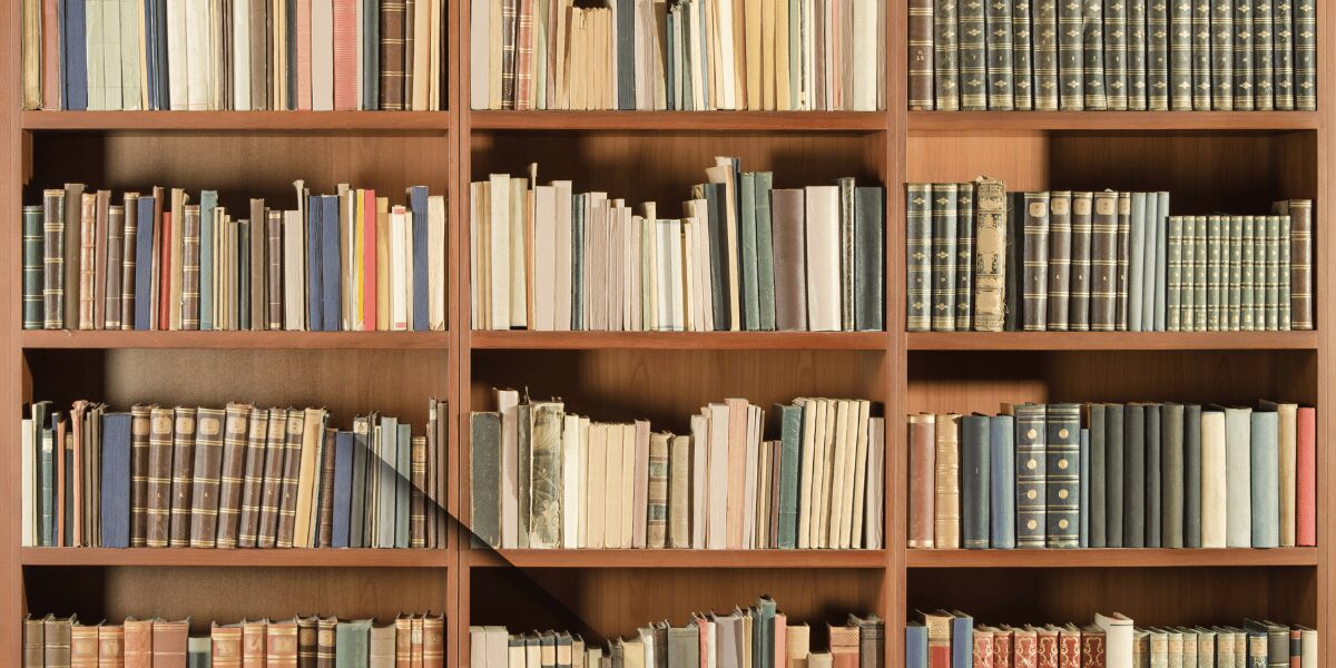 本がぎっしりと並んだ木製の書棚。物語が静かに息づく図書館の一角のような風景で、本の重みと温かみを感じさせる。